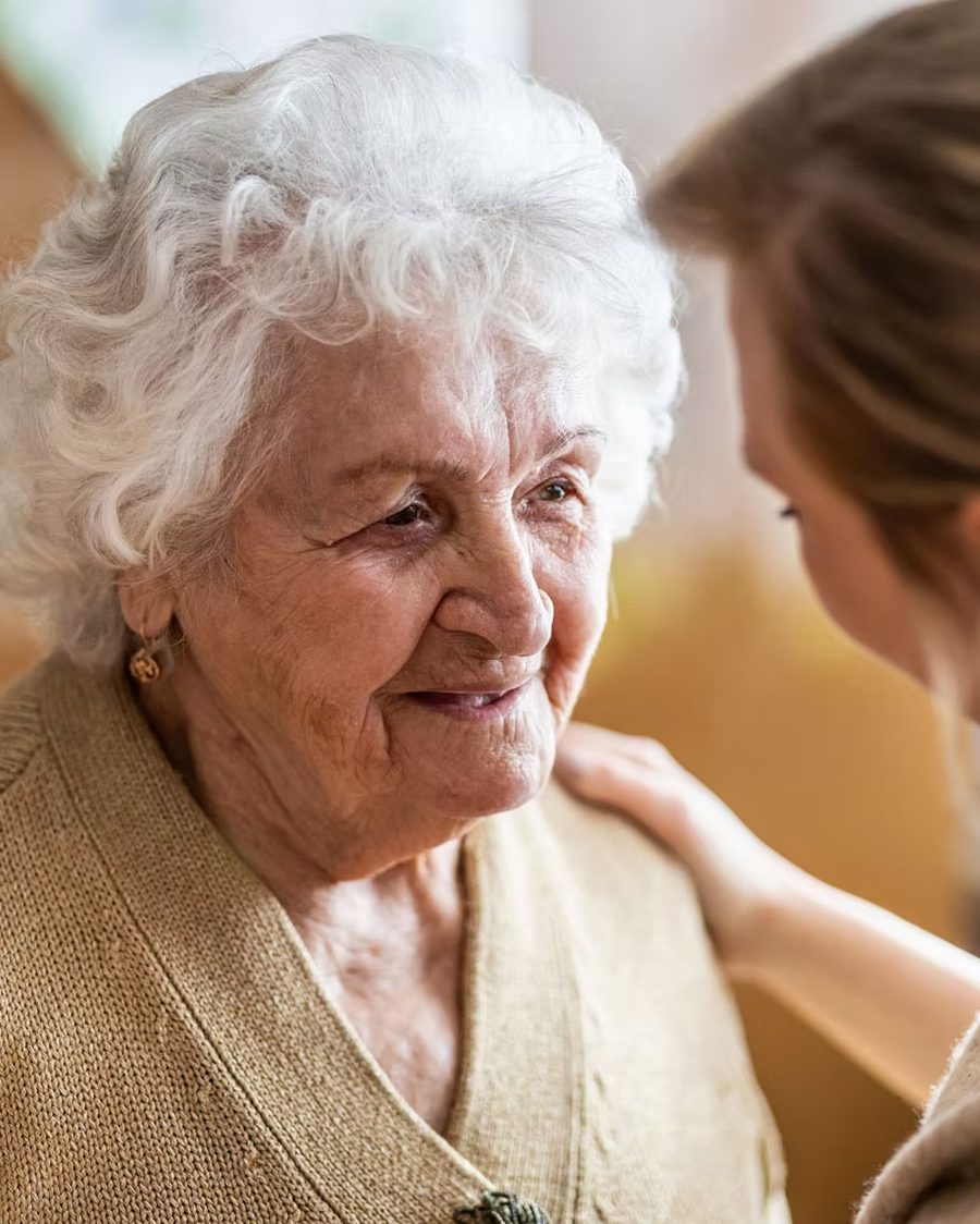 An older woman sitting with her carer at home