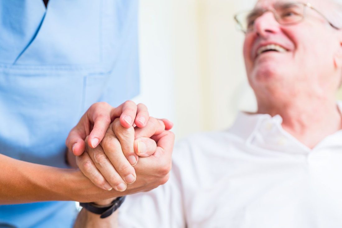 An older man laughing with his live-in carer at home
